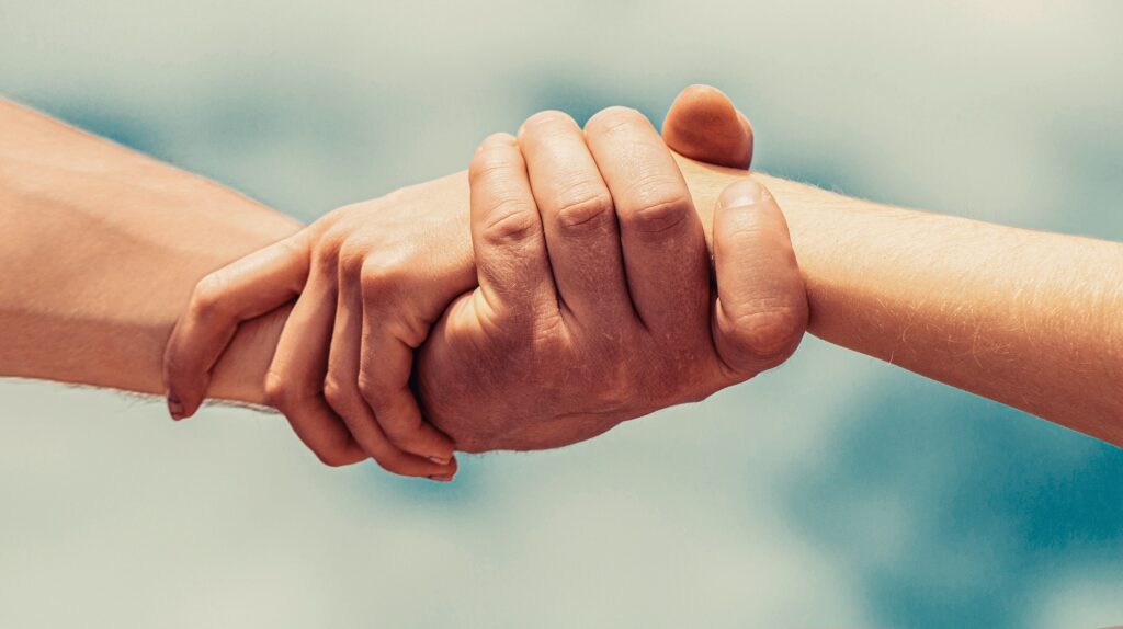 Two people holding hands as a sign of strength and cooperation